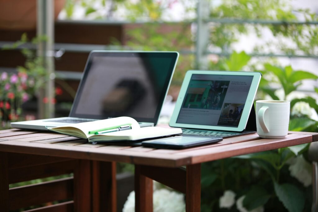 Two laptops on a table with an open book