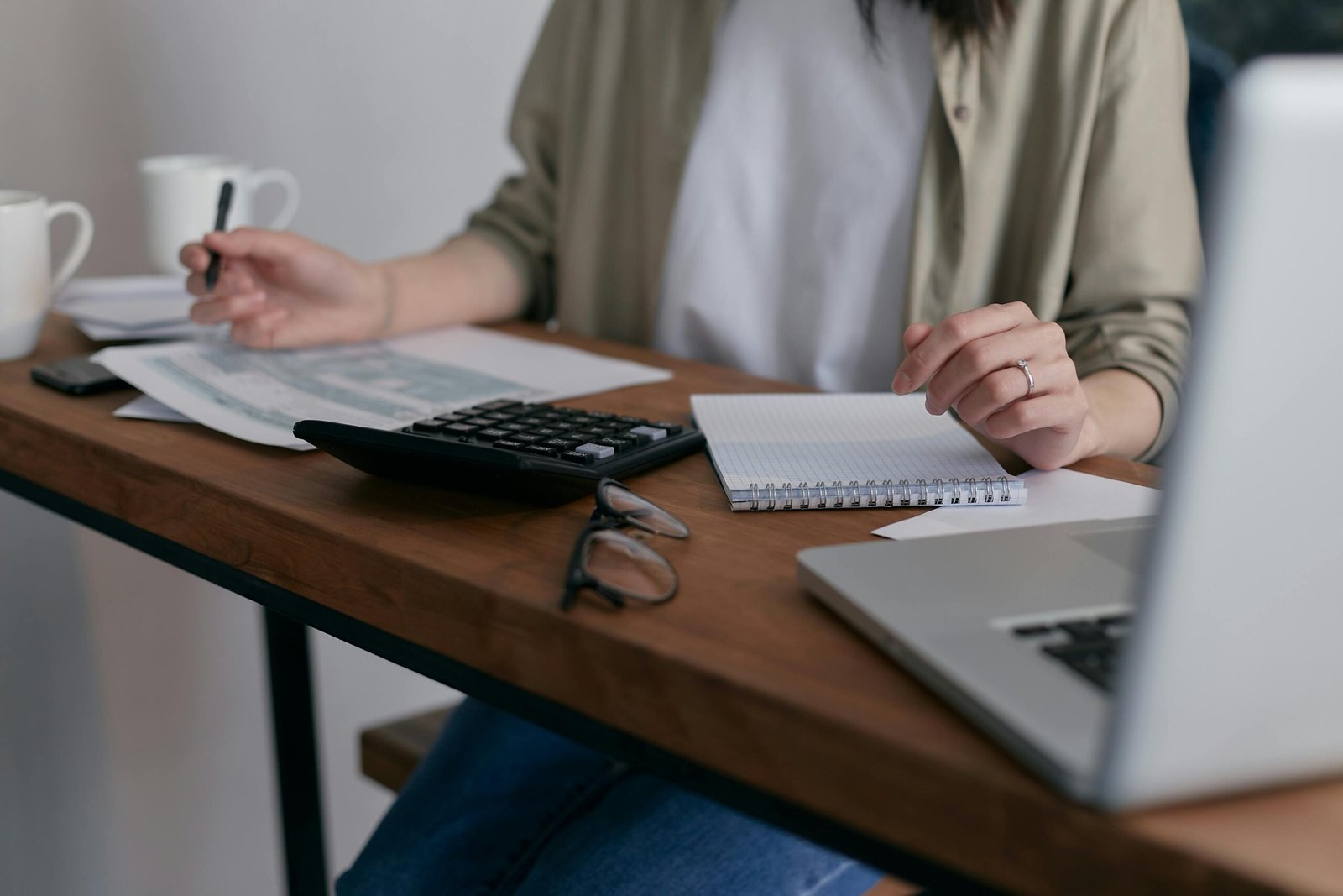 Woman working at a desk with an open laptop, calculator, and books